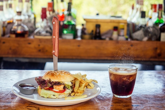 Бургер с креветками и напиток на стекле в тропическом баре рядом с пляжем