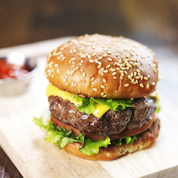 Burger with sesame bun and melted cheese close up