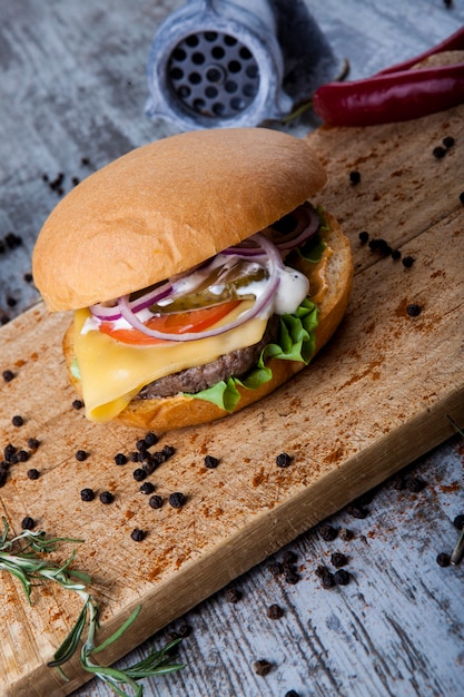 burger on wooden board with knife and grinder with pepper