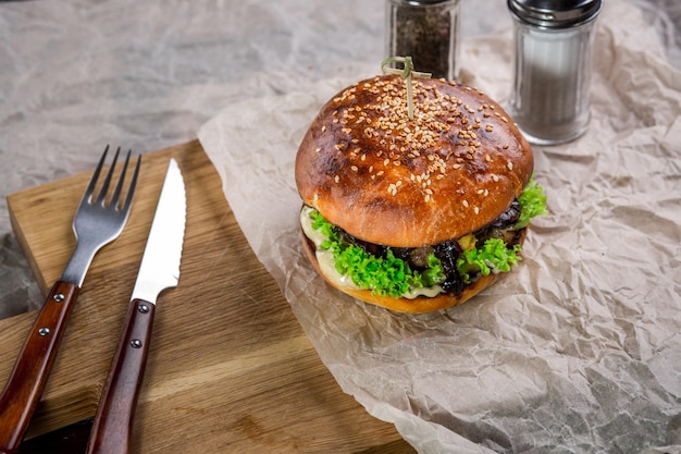 Burger on the wooden table with with knife and fork. burger with lamb