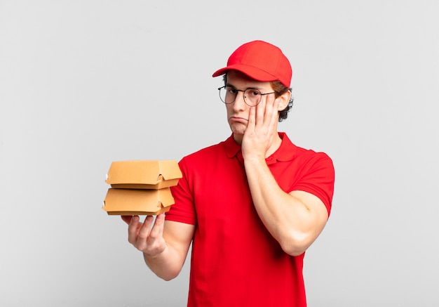 Burgers bezorgen jongen die zich verveeld, gefrustreerd en slaperig voelt na een vermoeiende, saaie en vervelende taak, gezicht met de hand vasthoudend