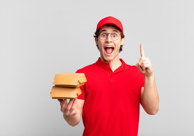 Burgers bezorgt jongen die zich een gelukkig en opgewonden genie voelt na het realiseren van een idee, vrolijk vinger opsteken, eureka!