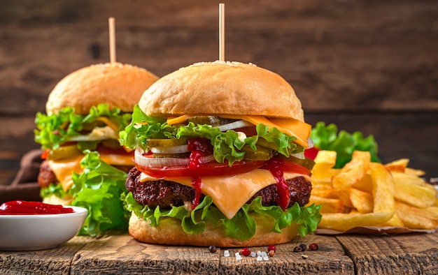 Burgers close-up on a brown background. Fast food. Two juicy burgers with meat, vegetables and cheese.