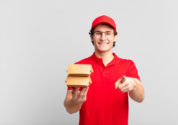 Gli hamburger consegnano il ragazzo che punta alla telecamera con un sorriso amichevole e fiducioso soddisfatto scegliendo te