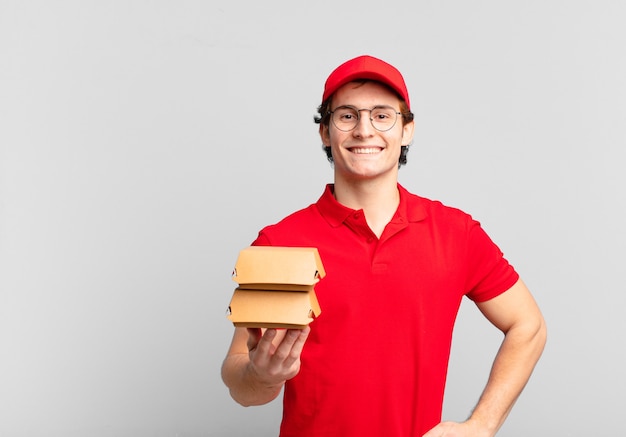 Burgers deliver boy smiling happily with a hand on hip and confident, positive, proud and friendly attitude