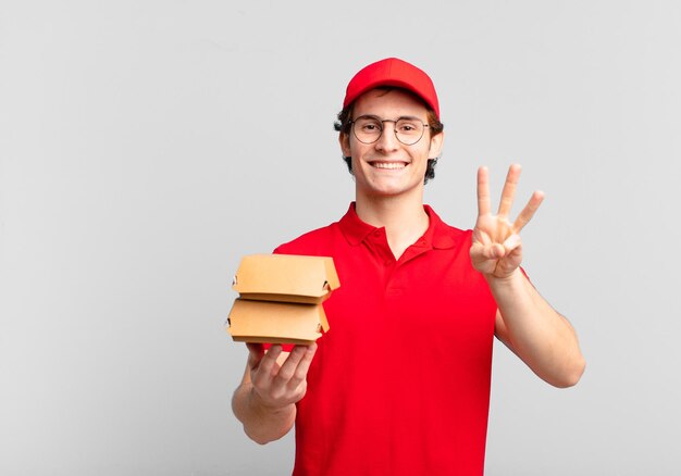 Burgers deliver boy smiling and looking friendly, showing number three or third with hand forward, counting down