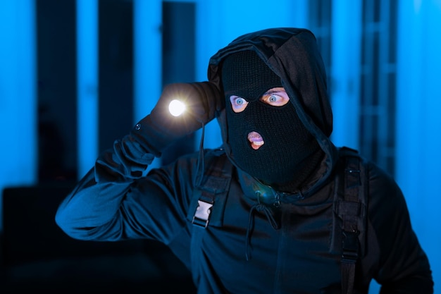 Photo burglar man with a flashlight searching intensely