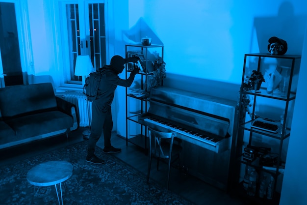 Photo burglar sneaking in a room with a piano