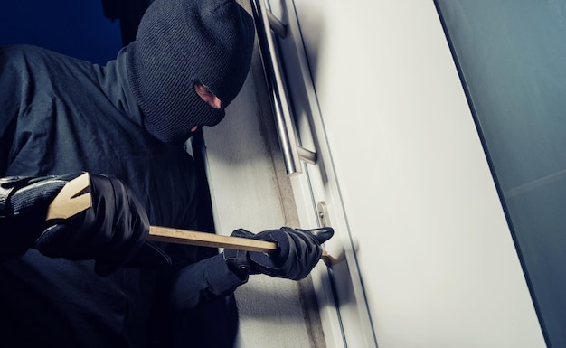 Burglar wearing black clothes and breaking in a house at night