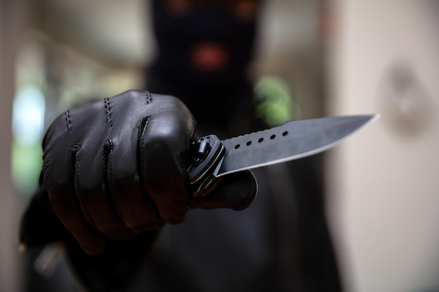 Фото Грабитель в балаклаве с ножом в руке в перчатке