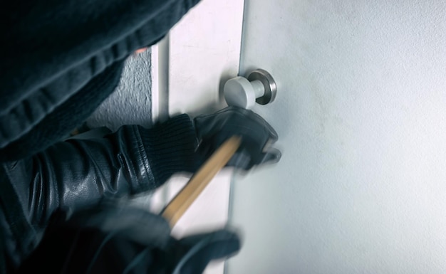 burglar with crowbar opens a house door at night