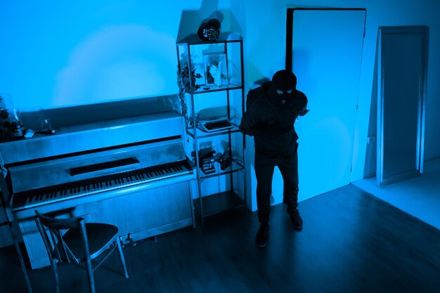 Burglar with full backpack examining dark room