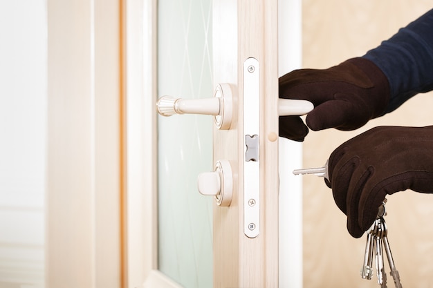 Burglar with lock picking tools breaking and entering into a house. Security concept.