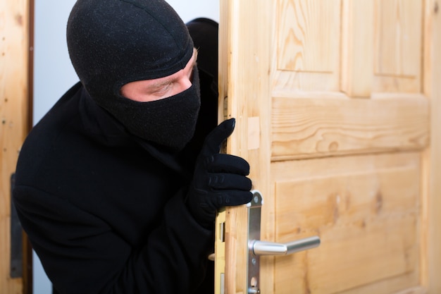 Foto crimine di furto con scasso - ladro che apre una porta
