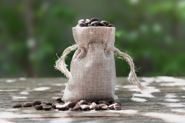 Burlap sack of coffee beans on old wood background