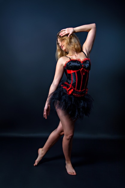 Burlesque dancer in short dress, black  background, on the stage
