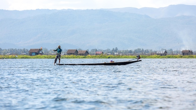 A Burmese fisherman drives a boat in the traditional way at Inle Lake, Myanmar