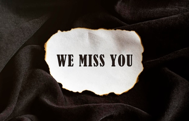 Photo burned paper on a black background with text we miss you