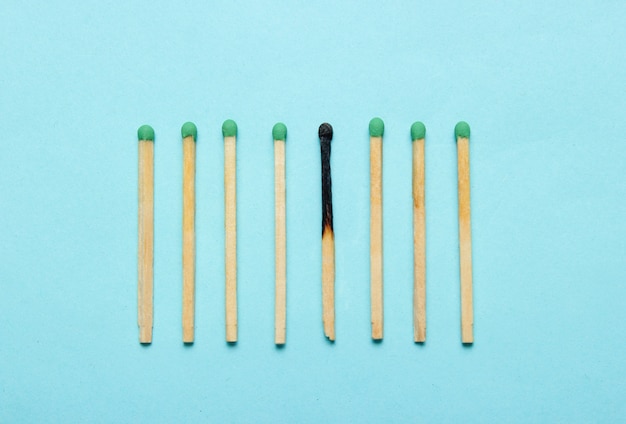 Burned and whole matches on a blue table. Minimalism concept