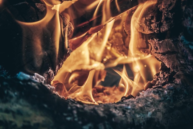 Burning bonfire with bright orange flames and sparks and hot charcoal against dark night sky