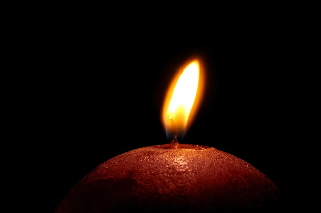 Photo burning candle on black background closeup