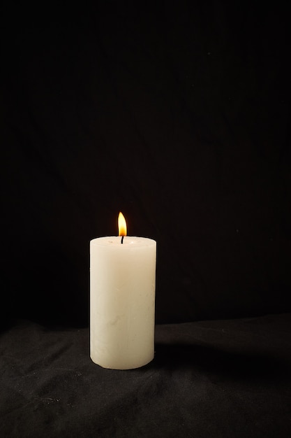 Burning candle on a black wall isolated.