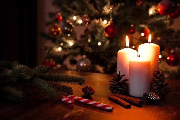 Photo burning candle and christmas ornaments against christmas tree