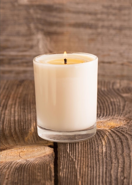 Burning candle in glass on wooden background