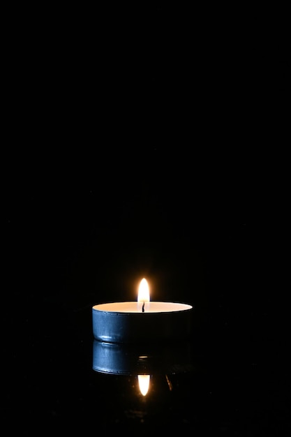 Burning candle and its reflection on a dark background