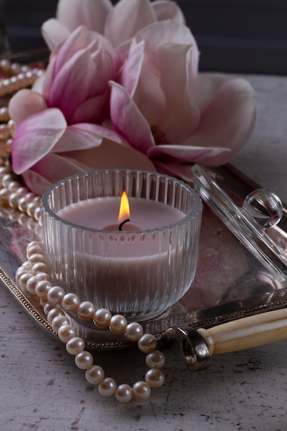 Burning candle and magnolia fresh flowers