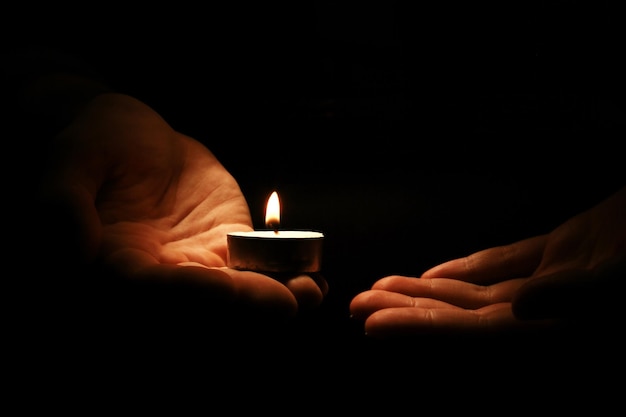 Burning candle in male hands, religion concept