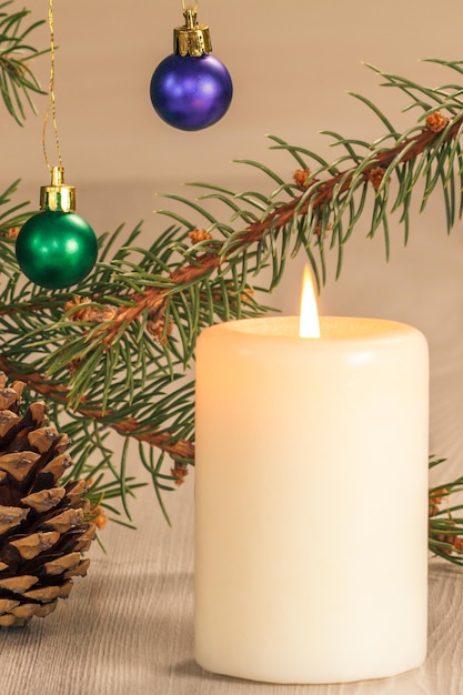 Burning candle and natural fir tree branches with Christmas ornament