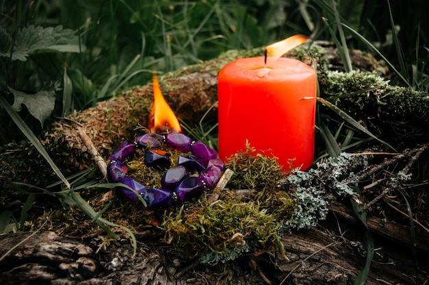 Candela accesa e un foglio di carta con numeri su uno sfondo naturale scuro pagan wiccan tradizioni slave stregoneria rituale spirituale esoterico per mabon halloween samhain festival dell'equinozio d'autunno