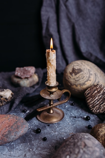 Burning candle and stones on the witch table occult esoteric concept