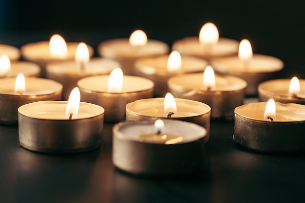 Burning candle on table in darkness, space for text. Funeral symbol