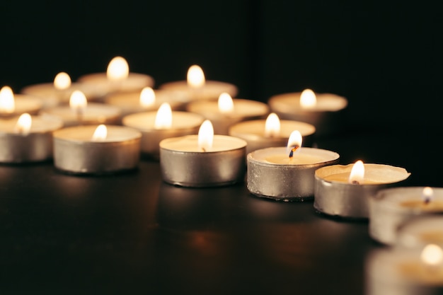 Burning candle on table in darkness, space for text. Funeral symbol