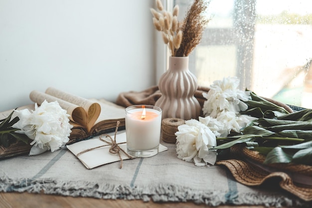 Photo burning candle and white peonies vintage aesthetic