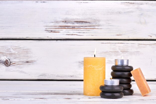 Burning candle with black stones and soap with copy space