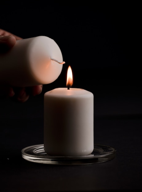 burning candle with flame mans hands lighting candle black background