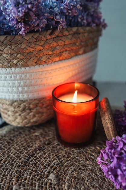 A burning candle with a wicker basket of lilacs Beautiful aesthetic photo