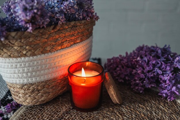 A burning candle with a wicker basket of lilacs Beautiful aesthetic photo