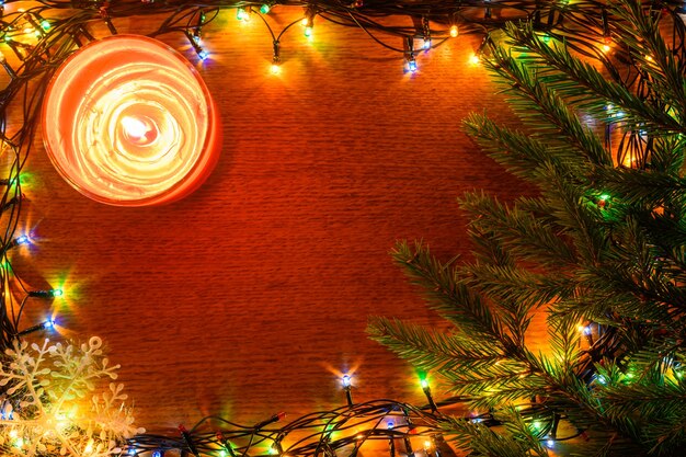 A burning candle on a wooden Christmas background with a spear space.