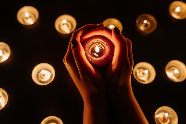 Burning candles. Candle in female hands. Many candles burning at night. Many candle flames glowing.