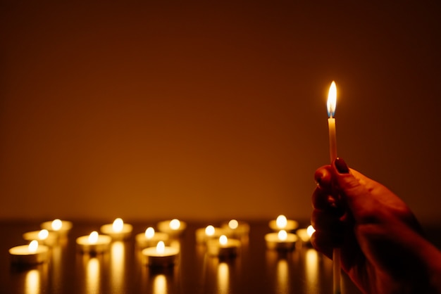 Burning candles. Candle in female hands. Many candles burning at night. Many candle flames glowing.