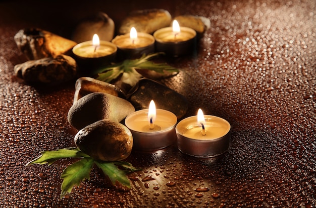 Burning candles and drops of water. Stone therapy. Spa treatments.