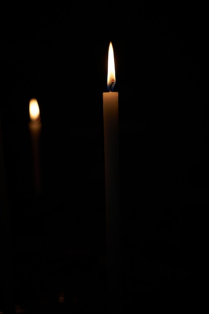 Photo burning candles glowing in dark isolated on black church