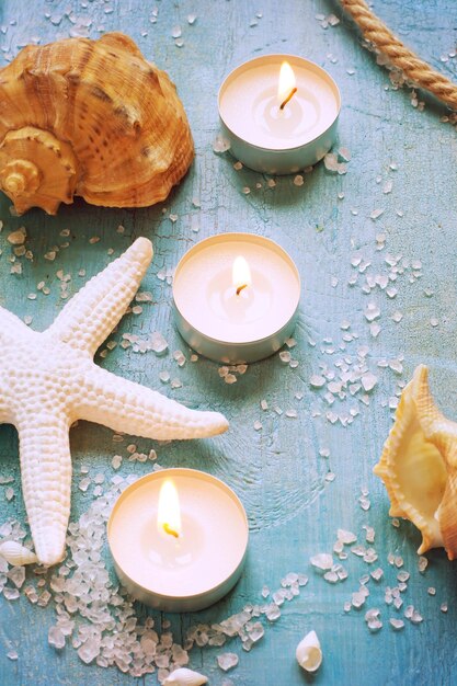 Burning candles and marine items on a turquoise background tinted