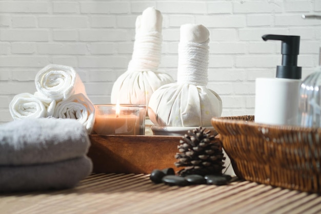 Photo burning candles for relax spa massage towels herbal compress balls and body treatment on wooden table