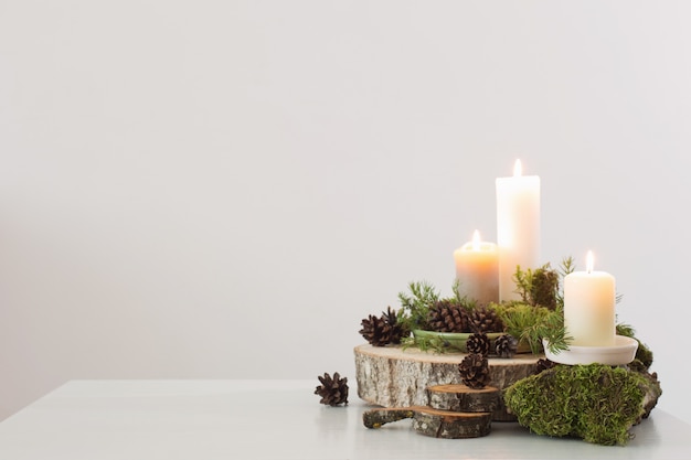 Burning candles on saw with cones and branches on white backgrou