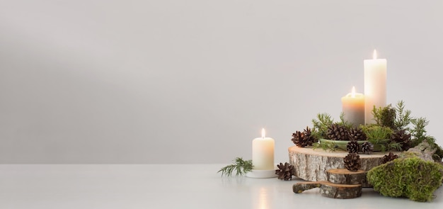 Photo burning candles on saw with cones and branches on white background